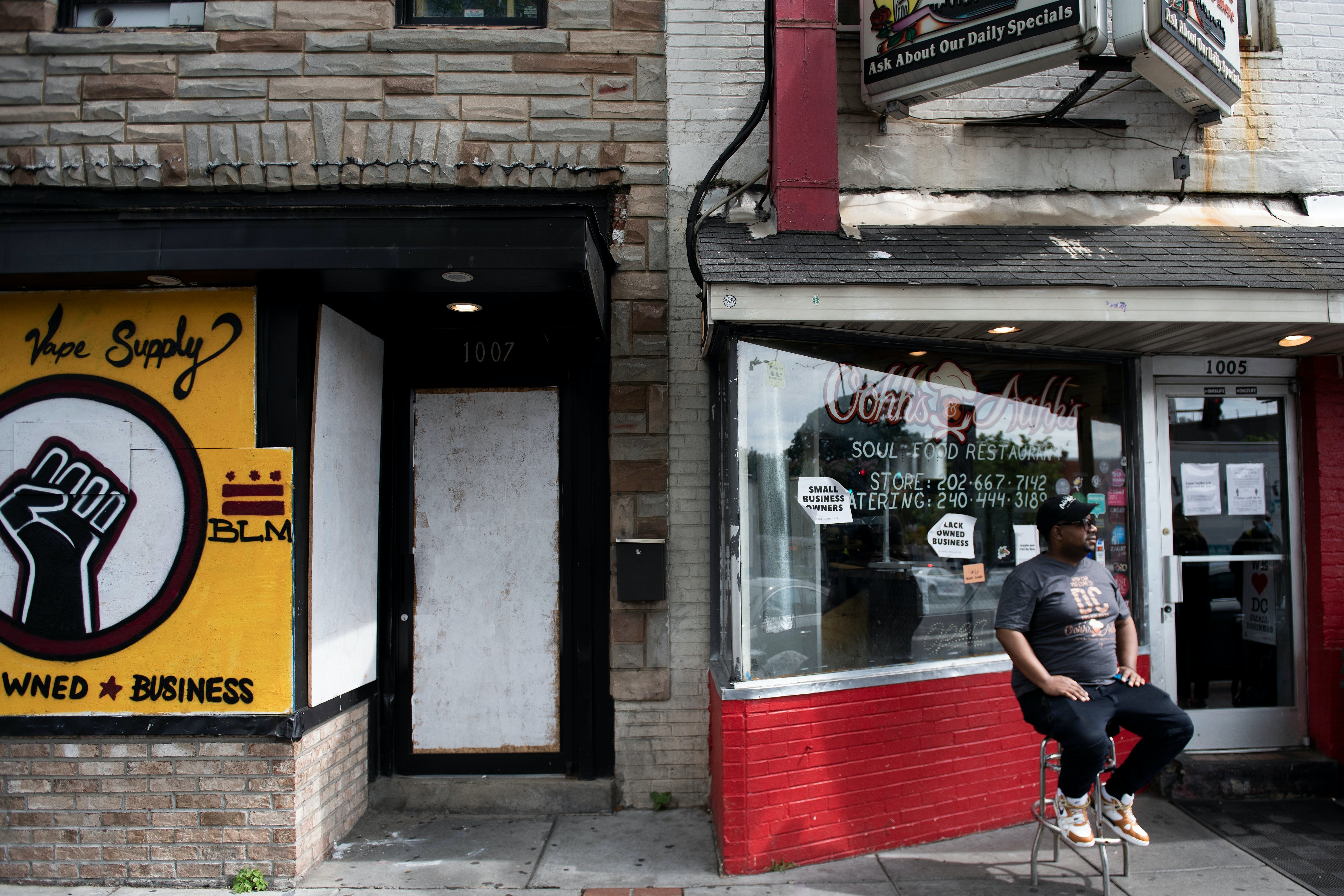 Chef Oji Abbot sits outside his restaurant and another Black-owned business, both of which feature anti-racism messaging