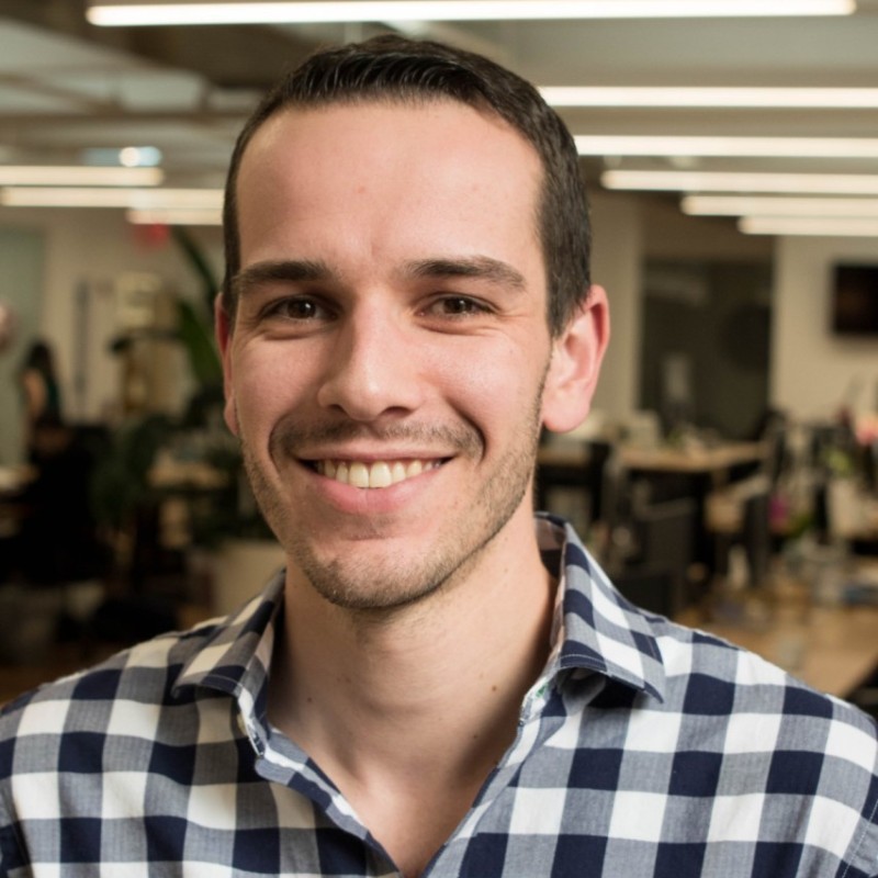 Un homme en chemise rayée et souriant à la caméra